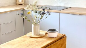 A kitchen with a wooden table, a vase with flowers, and a hanging pot rack. - Woodview - Idyllic Cottage in the Country (Kinnettles)