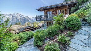 A wooden cabin with a balcony, surrounded by lush greenery and stone steps, overlooking a mountainous landscape. - Chalet La Vue (Les Crettaux - Nendaz) (Isérables)