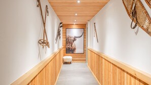 A hallway with wooden paneling, a white floor, and wall-mounted decor including a framed picture of a yak. - Chalet La Vue (Les Crettaux - Nendaz) (Isérables)