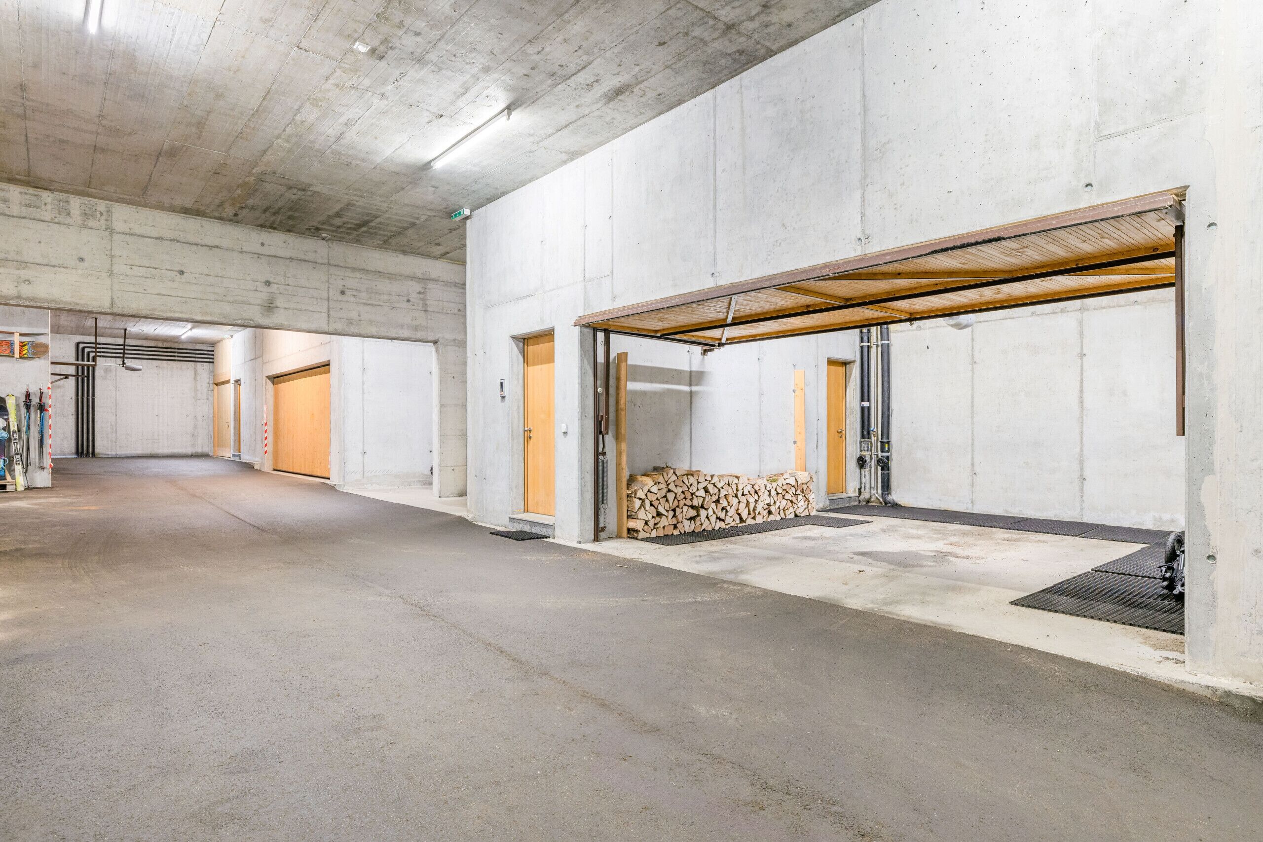 Un vaste espace intérieur aux murs en béton et au plafond haut, doté de plusieurs portes et d’une zone de chargement couverte.