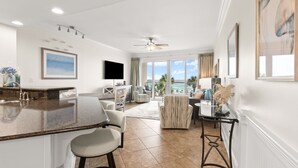 A modern kitchen with a bar area, a dining set, and a living area with a view of the ocean.