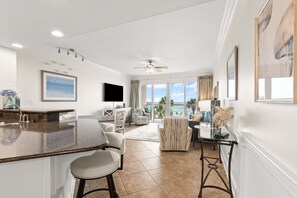Una cocina moderna con barra, comedor y sala de estar con vista al océano.