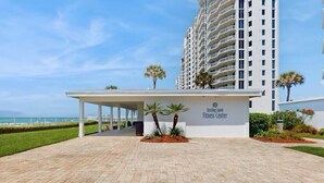 A Sterling Sands Fitness Center with a covered entrance, palm trees, and a view of the ocean.