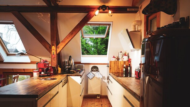 Una cucina angusta con travi in legno, una finestra vista verde e una macchina da caffè rossa.