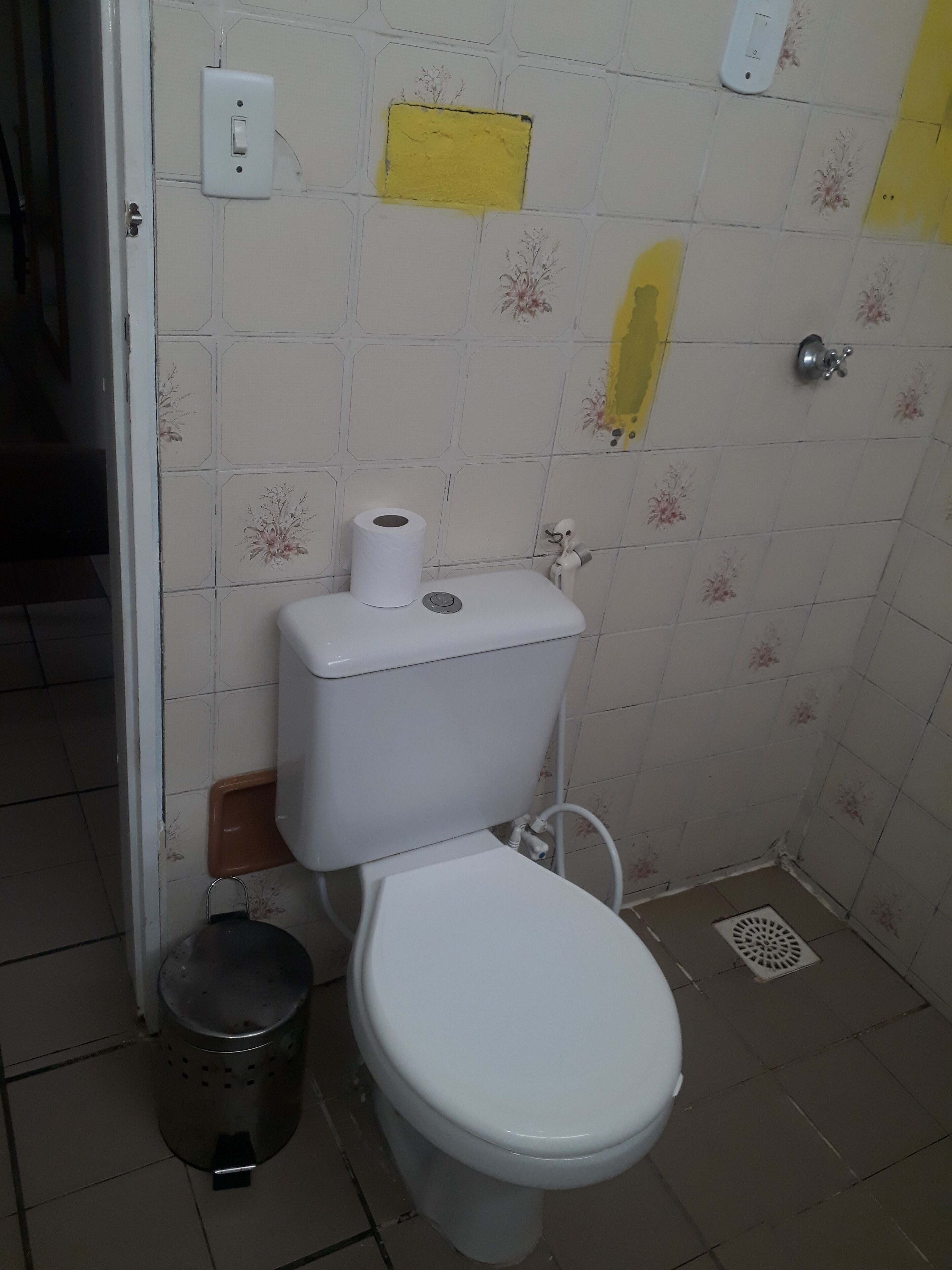 Une petite salle de bain avec des toilettes, une poubelle et un drain de douche.