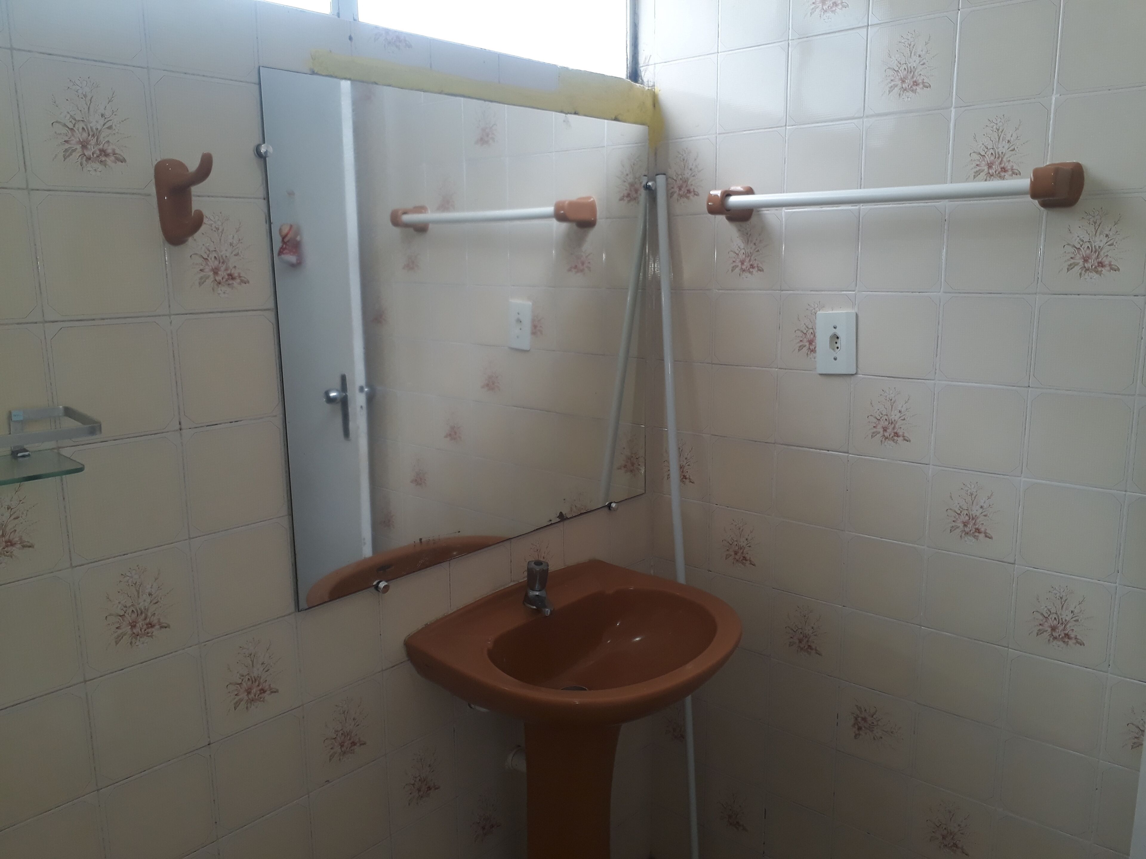 Ett badrum med ett brunt handfat, en spegel och en handdukshängare.