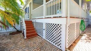 A covered porch with a white railing, brick steps, and a lattice fence. - Cabana at the Golf Club-Monthly Rental Charming 2- (Key West)