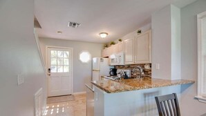 A kitchen with white cabinets, a granite countertop, a refrigerator, and a microwave. - Cabana at the Golf Club-Monthly Rental Charming 2- (Key West)