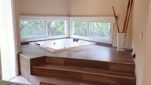 Une pièce dotée d’une grande fenêtre, d’une baignoire et d’un escalier en bois.