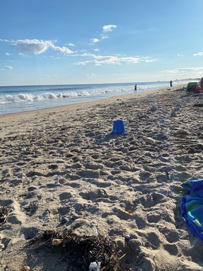 Une plage de sable parsemée de rochers et un seau bleu.