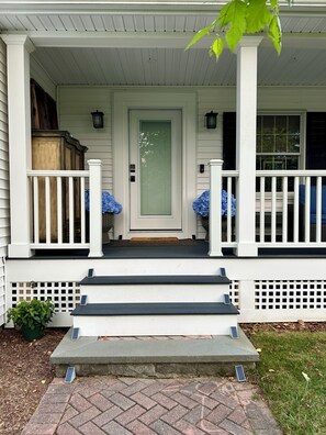 A house with a front porch, a door with a window, and steps leading to the entrance.