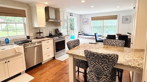 A modern kitchen with white cabinetry, a granite countertop, and patterned chairs. - Spacious 5bdrm home- saltwater pool, WiFi, AC, private beach parking pass (Westerly)
