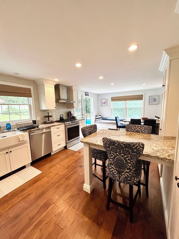 A modern kitchen with white cabinetry, a granite countertop, and patterned chairs.
