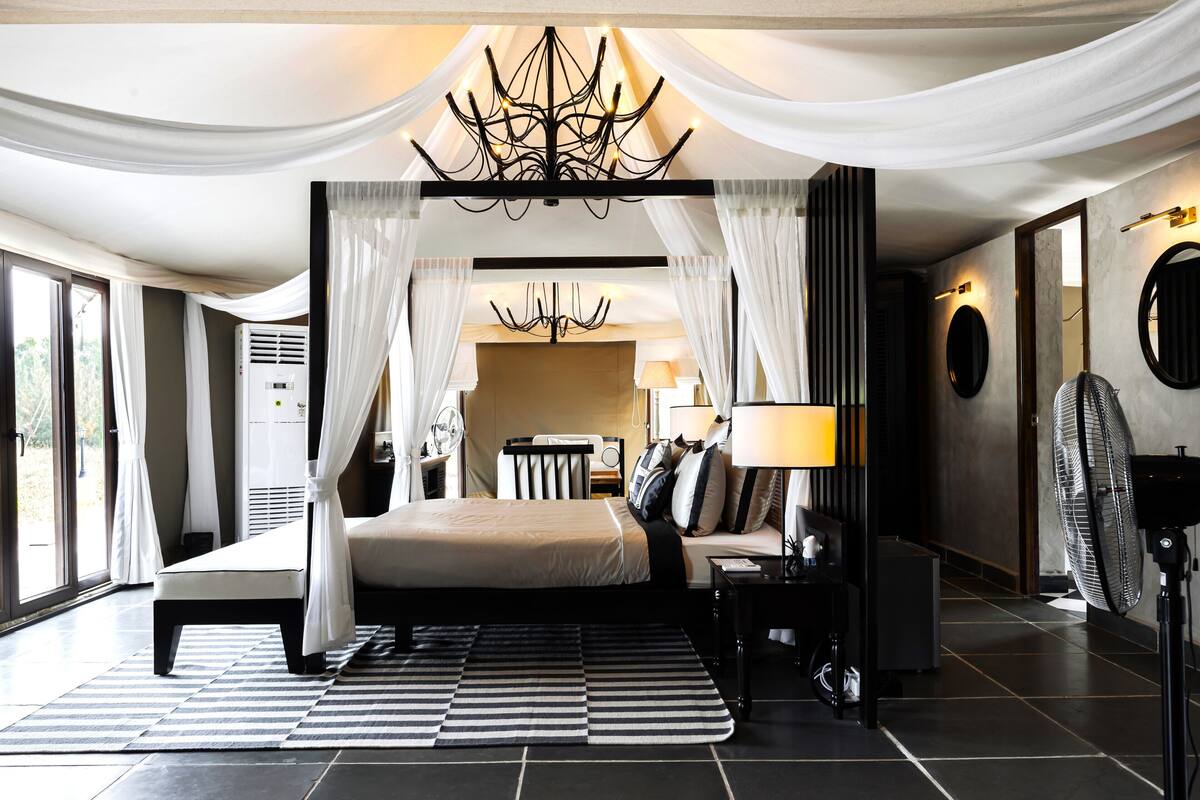 A spacious bedroom with a large bed, a sitting area, a ceiling fan, and a view of the outdoors.
