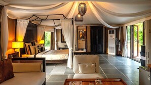 A spacious room with a bed, a sofa, a dining table, and a view of the outdoors. - The Alampara resort (Cheyyur)