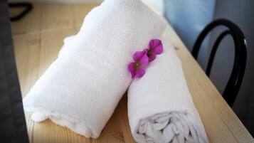 Two white towels with a purple flower on a wooden table.