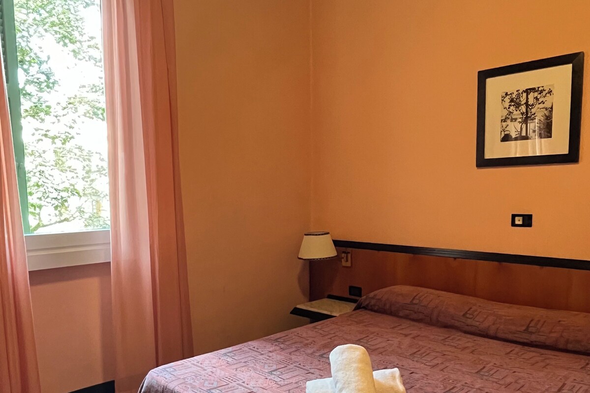 A hotel room with a bed, a nightstand, a lamp, and a framed picture on the wall.