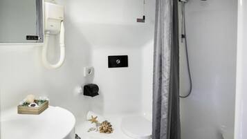 Un baño con lavamanos, inodoro y ducha blancos. Hay un perchero con un adorno de estrella y una pequeña caja de madera con artículos de aseo.