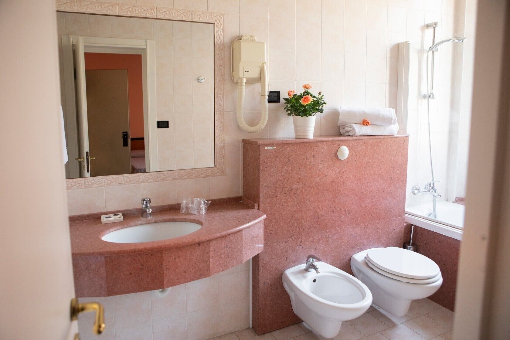 A bathroom with a sink, bidet, toilet, and a shower.