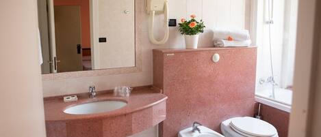A bathroom with a sink, bidet, toilet, and a shower.