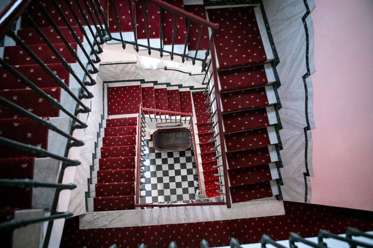 A spiral staircase with red steps and a checkered floor.