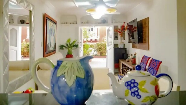 A room with a table, a blue vase, a white teapot, and a doorway leading to an outdoor area with plants and a view of a building. - Entire rented housing in Cartagena de Indias, Colombia (Cartagena de Indias)