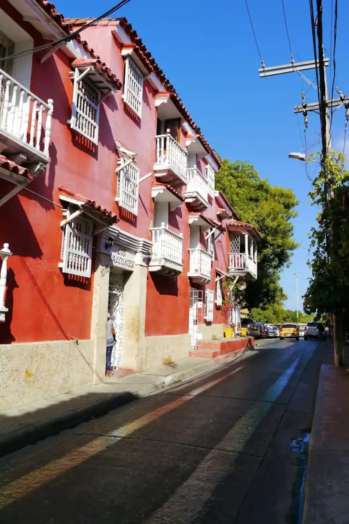 A red building with balconies and a sign that reads "Los Alcacenes".