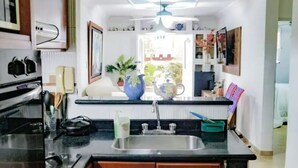 A kitchen with a central island, a sink, and a stove. There is a ceiling fan, a window, and a door leading to another room. - Entire rented housing in Cartagena de Indias, Colombia (Cartagena de Indias)
