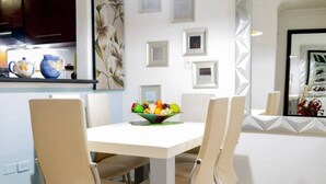 A dining area with a white table and four chairs, a fruit bowl on the table, and a hanging light fixture. - Entire rented housing in Cartagena de Indias, Colombia (Cartagena de Indias)