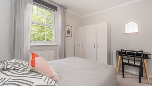 Un dormitorio con cama, escritorio y armario.