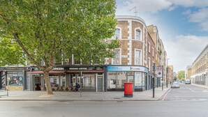 Vista de la calle con un edificio en esquina que tiene una cafetería y un letrero que dice Kings Cross.