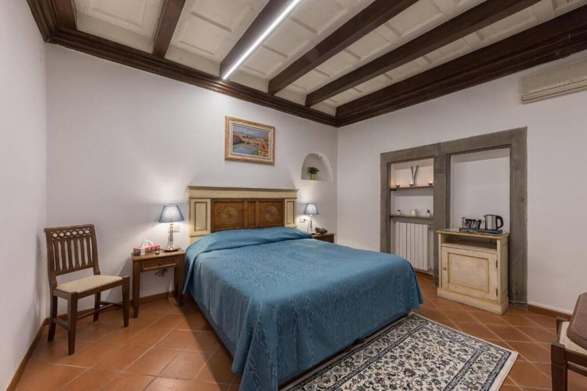 Une chambre à coucher comprenant un lit, une chaise, un bureau, une lampe, une étagère et un miroir.
