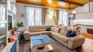 Una sala de estar acogedora con un sofá color beige, una mesita de centro y una cocina al fondo.