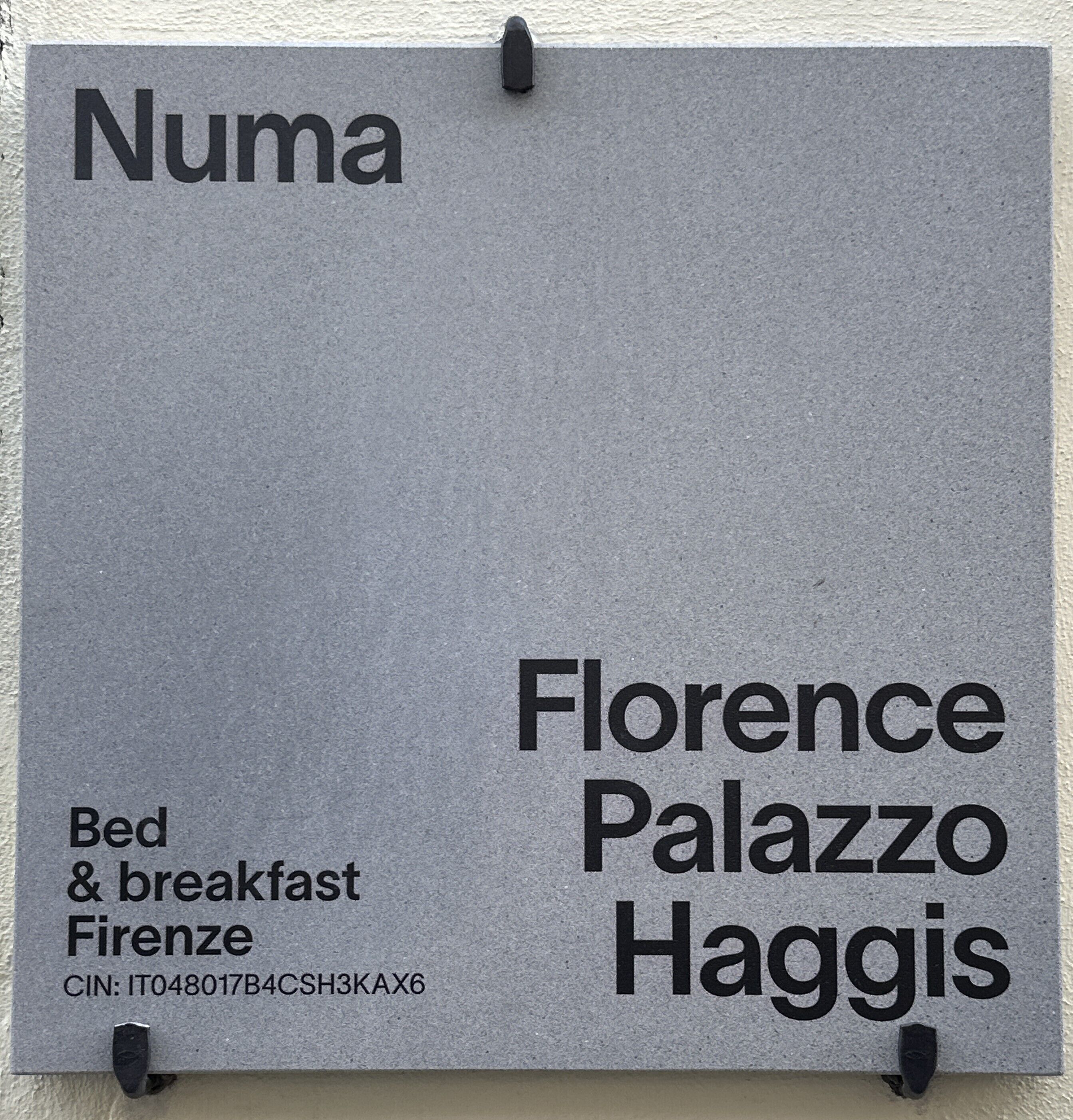 Une enseigne indiquant « Florence Palazzo Haggis », précisant qu’il s’agit d’un hôtel proposant également un service de chambre et de petit-déjeuner à Florence.