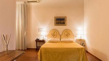 Un dormitorio con cama, dos mesitas de noche, lámpara, un cuadro en la pared y cortina.