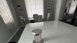 Una cocina con una isla grande, un refrigerador y un comedor con sillas.