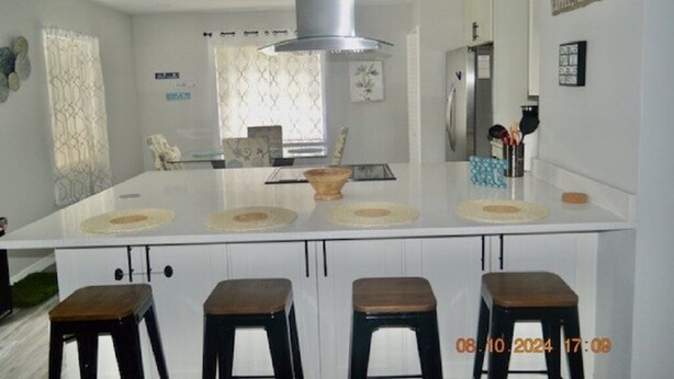 Una cocina moderna con una isla central, armarios blancos y una campana extractora de acero inoxidable.