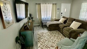 Una sala de estar con sofá, sillón, televisor y alfombra de diseño geométrico.