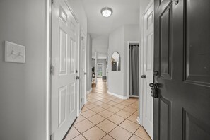 A hallway with white doors, a tiled floor, and a ceiling light.
