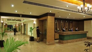 Een hotel lobby met een receptiebalie, een wachtruimte en een gang naar andere kamers.