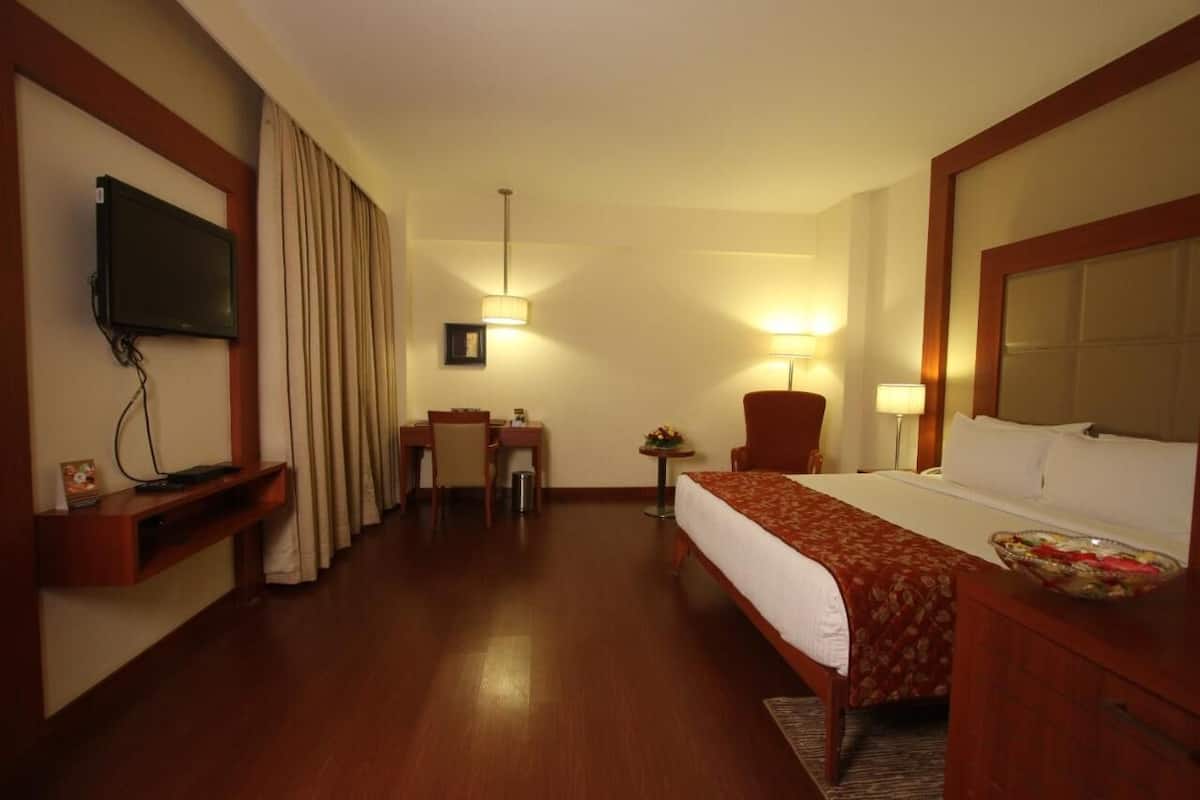 Een hotelkamer met een bed, een bureau, een stoel, een televisie en een tafeltje met een lamp.