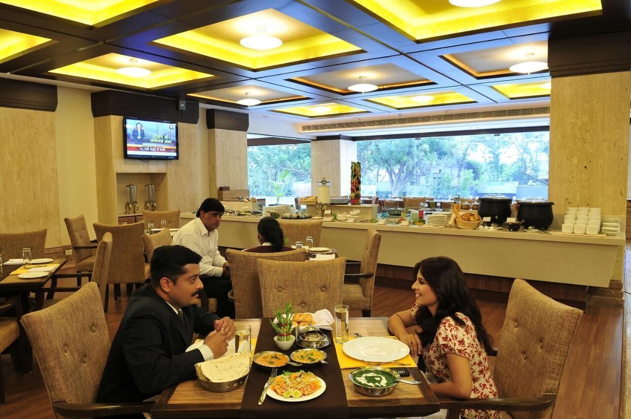 A restaurant with multiple dining tables, chairs, and a television screen on the wall.