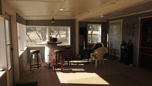 A room with a bar area, two stools, a chair, and a view of the outdoors. - Mason Ranch Guest House (Mason)