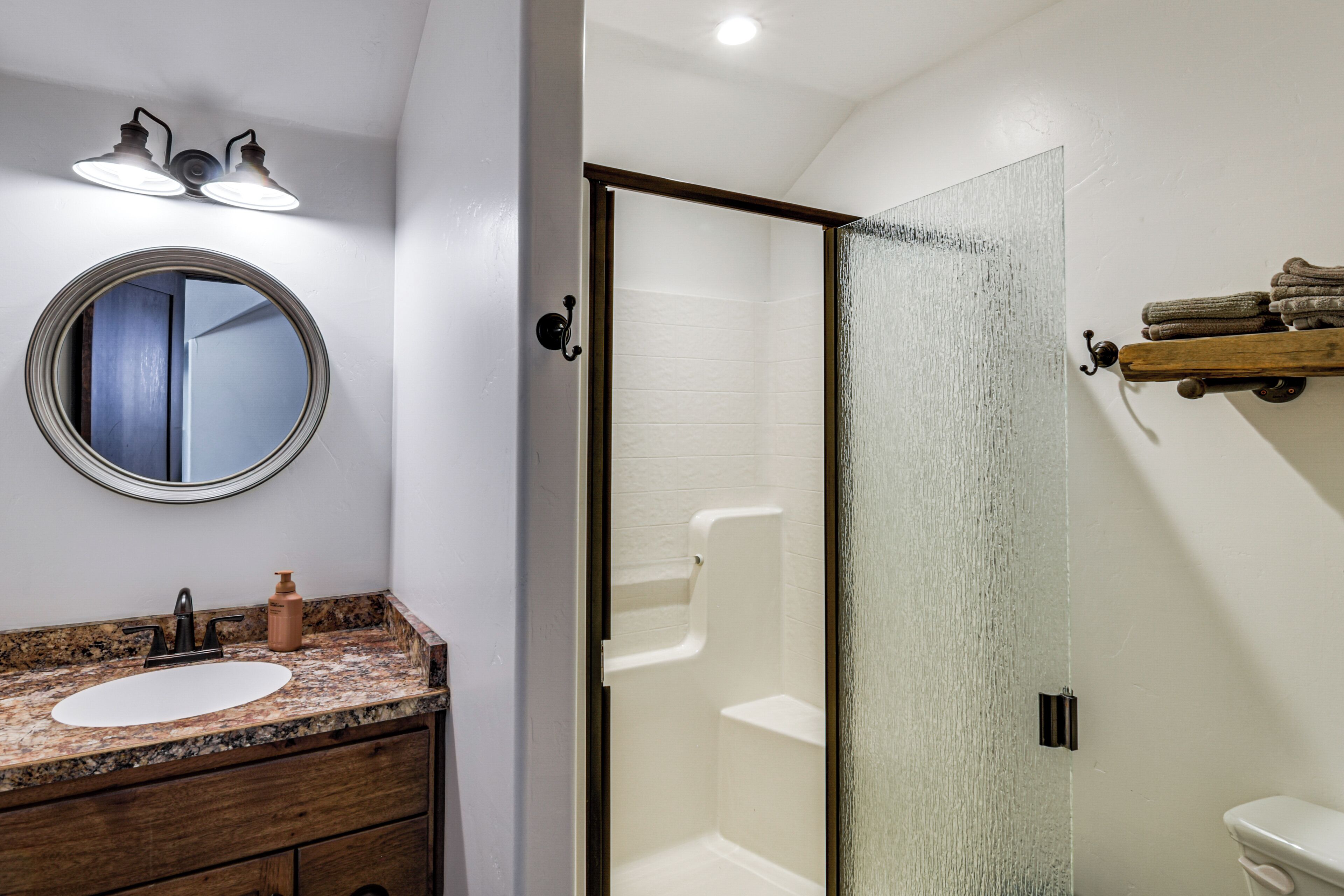 A bathroom with a sink, mirror, towel rack, and shower.
