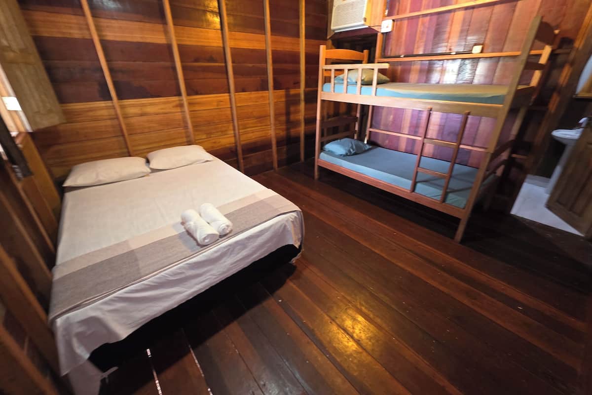 A wooden room with a bunk bed, a single bed, and a small seating area.
