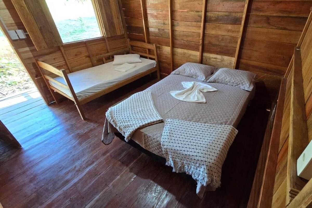 A wooden cabin room with a bed and a bench.