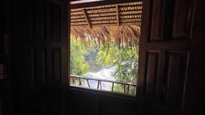 A window with a view of a river and greenery, framed by a wooden structure. - Pousada Cabana Nativa Paraíso (Careiro)
