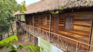 A wooden cabin with a thatched roof, a wooden deck, and a sign indicating it is a native fish and ecotourism site. - Pousada Cabana Nativa Paraíso (Careiro)