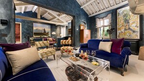 Ein modernes Wohnzimmer mit blauen Sofas, einem Glastisch und Kunstwerken an den Wänden.