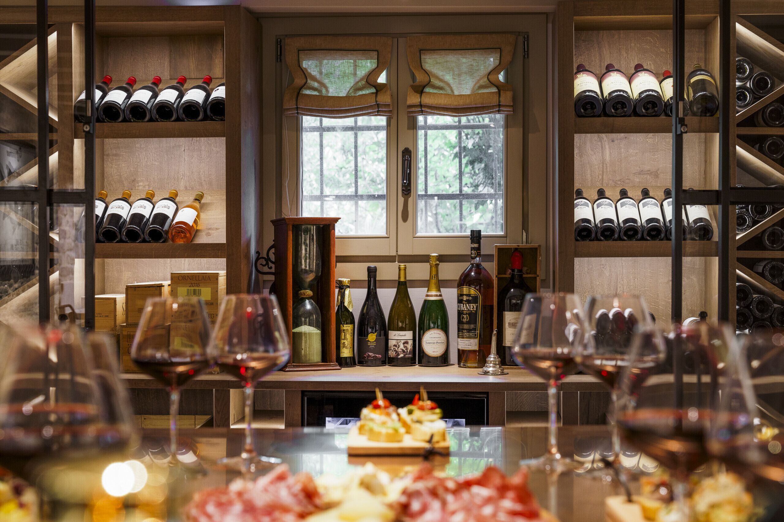 A wine cellar with shelves of wine bottles and glasses of wine on a table.